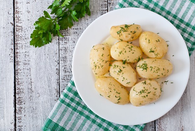 Young boiled potatoes with butter and dill on a white plate