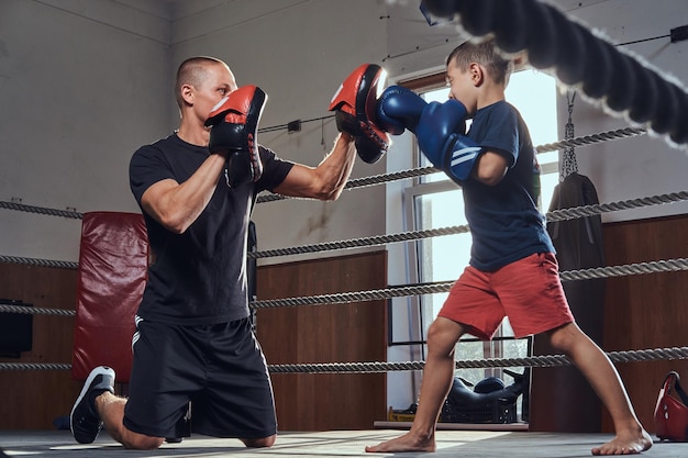 Молодой тренер боксера тренирует нового мальчика-боксера для специальных соревнований.