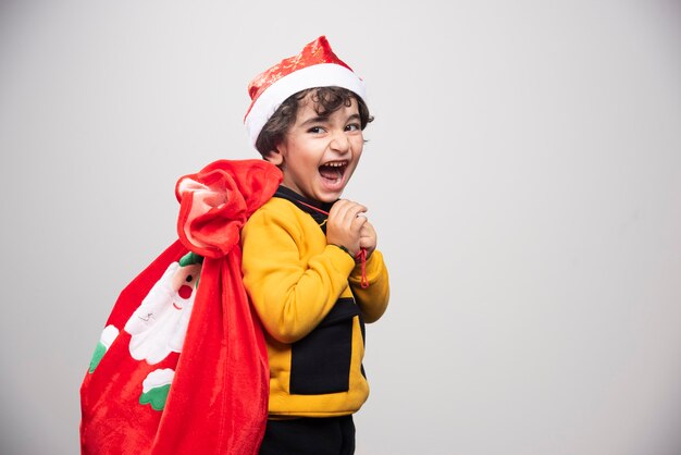 Young boy as Santa Claus holding red gift bag