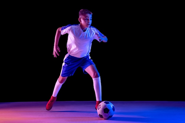 Молодой мальчик как футболист или футболист в темной студии