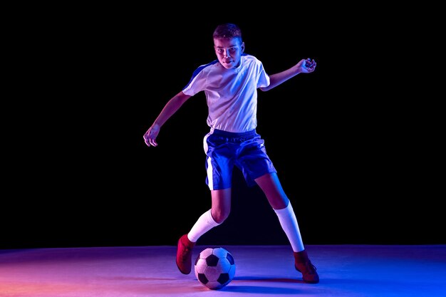 Young boy as a soccer or football player on dark  wall