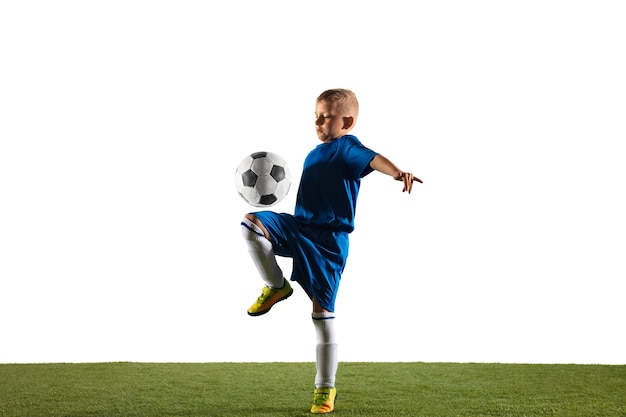 Young boy as a soccer or football player in sportwear making a feint or a kick with the ball for a goal on white  background. Free Photo