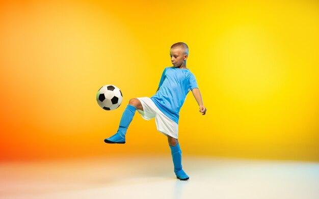 グラデーション黄色で練習しているスポーツウェアのサッカーまたはサッカー選手としての少年