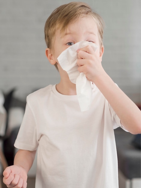 Free photo young boy blowing nose