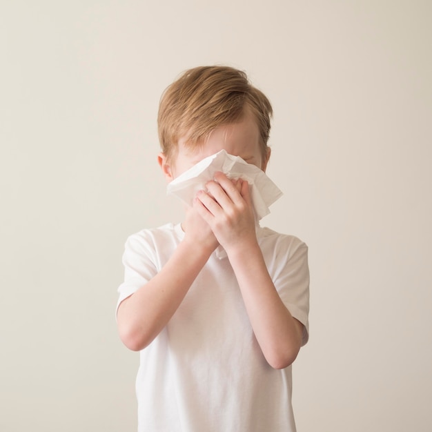 Free photo young boy blowing nose