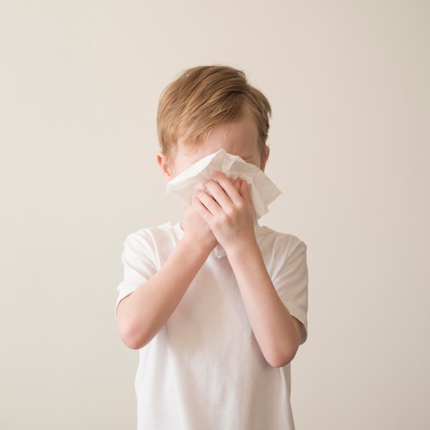 Young boy blowing nose