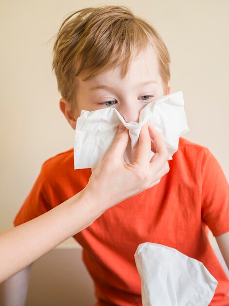 Young boy blowing nose