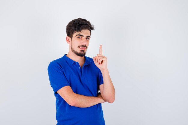 Young boy in blue t-shirt raising index finger in eureka gesture and looking sensible , front view.