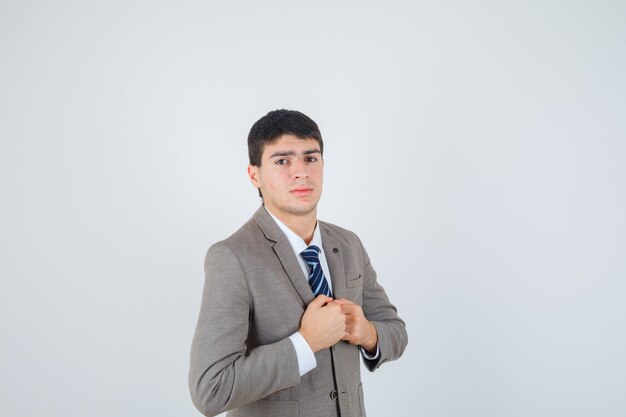Young boy clenching fists over chest in formal suit