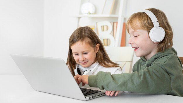 Young boy and girl using laptop with headphones