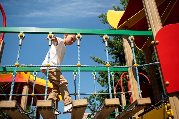 Молодой мальчик развлекается на детской площадке на открытом воздухе