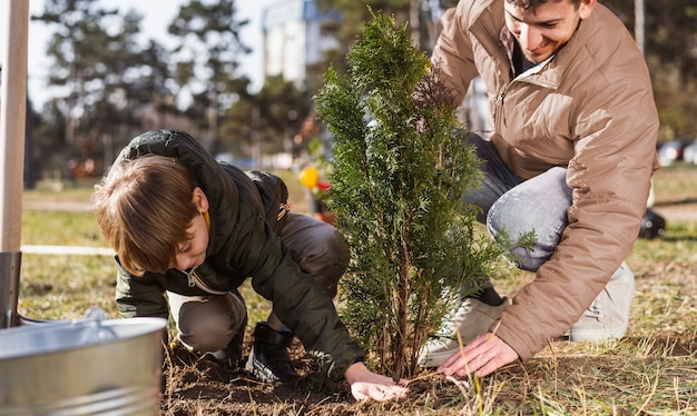 少年と彼の父は屋外で木を植える