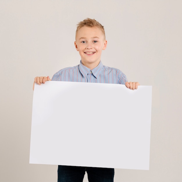 Молодой мальчик держит чистый лист бумаги