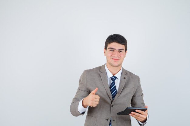 Young boy holding calculator, showing thumb up in formal suit