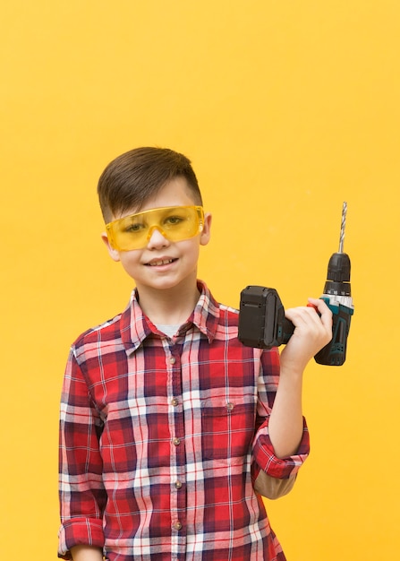 Free photo young boy holding drilling machine