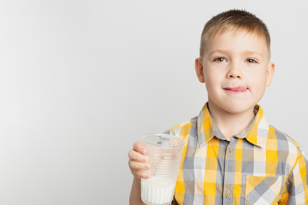 Foto gratuita giovane ragazzo che tiene bicchiere di latte