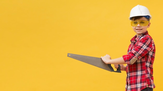 Young boy holding saw tool copy space