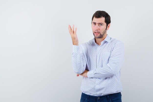 The young boy is raising his right hand up with displeasure on  white background.