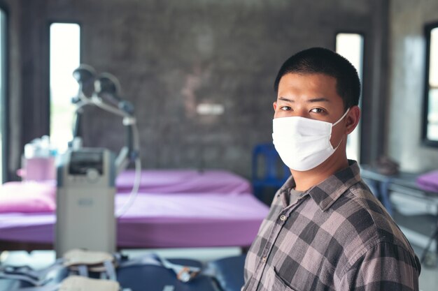 Young boy is waring mask  ,feeling chest pain  and sitting on the hospital for meet doctor.