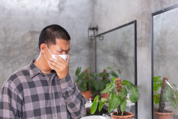 Young boy is waring protect mask and close his mouth by hand for protect virus on the rest room .- concept mask campaign.