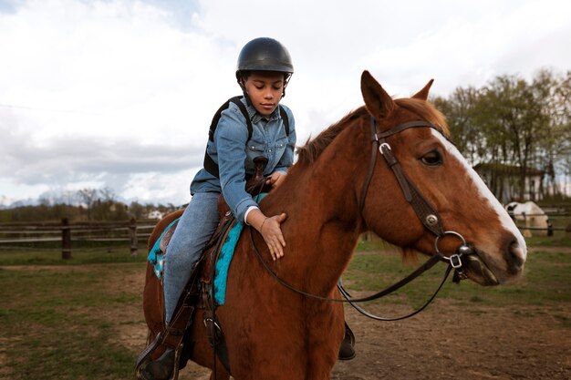 Молодой мальчик учится кататься на лошади