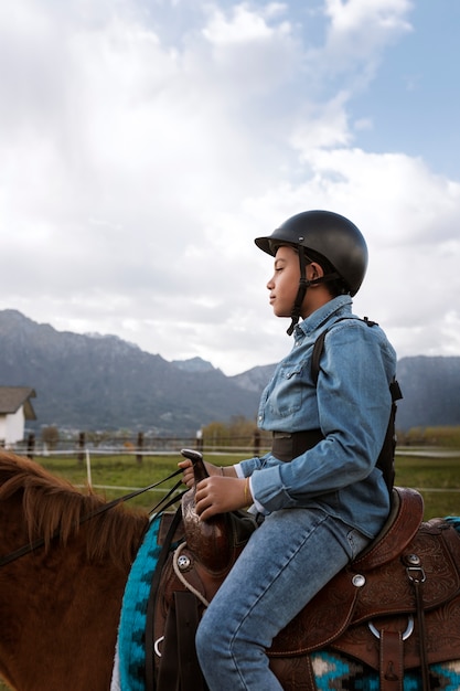 Free photo young boy learning how to ride horse