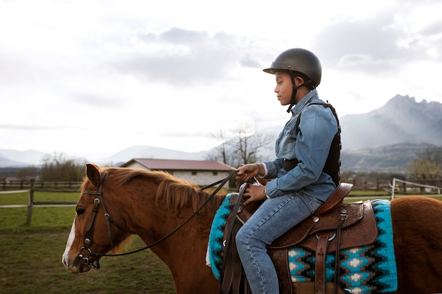 Free photo young boy learning how to ride horse