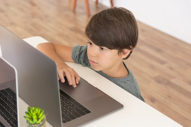 Free photo young boy looking on laptop