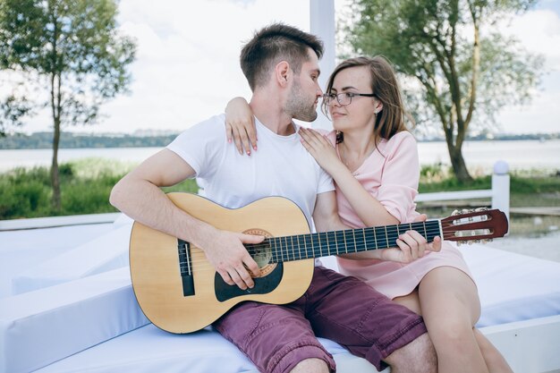 Young boy playing the guitar to his girlfriend while she hugs him