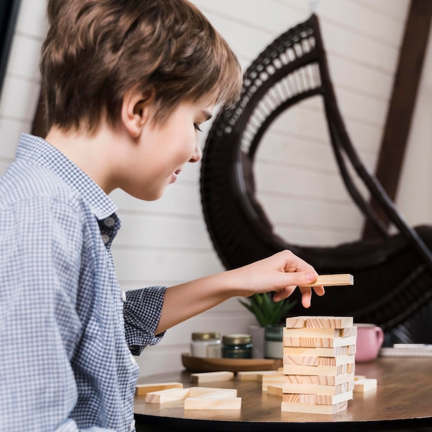 Foto gratuita giovane ragazzo che gioca jenga a casa