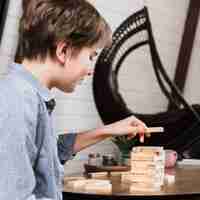 Free photo young boy playing jenga at home