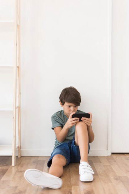 Молодой мальчик, играя на смартфоне
