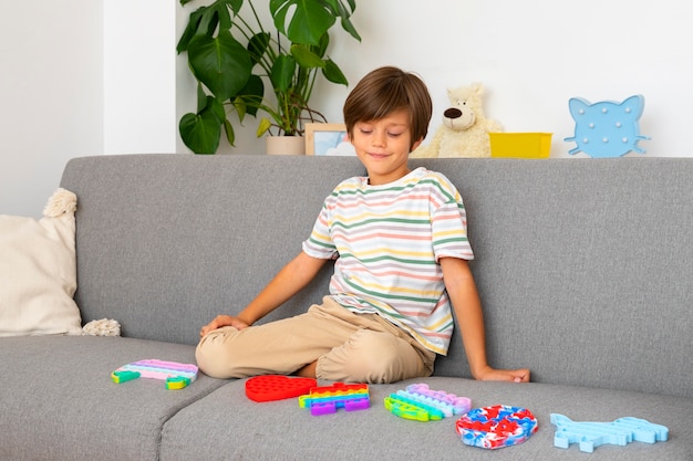 Бесплатное фото Маленький мальчик играет с беспокойной игрушкой дома