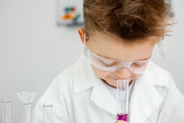 Young boy scientist doing experiments in the laboratory while wearing safety glasses