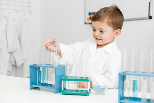 Free photo young boy scientist with test tubes