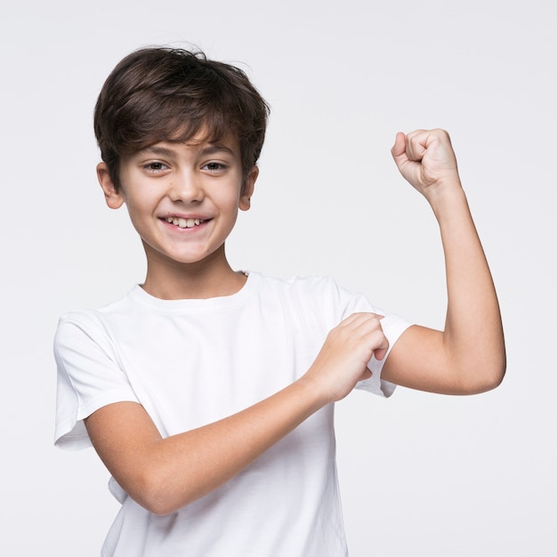 Free photo young boy showing his muscle