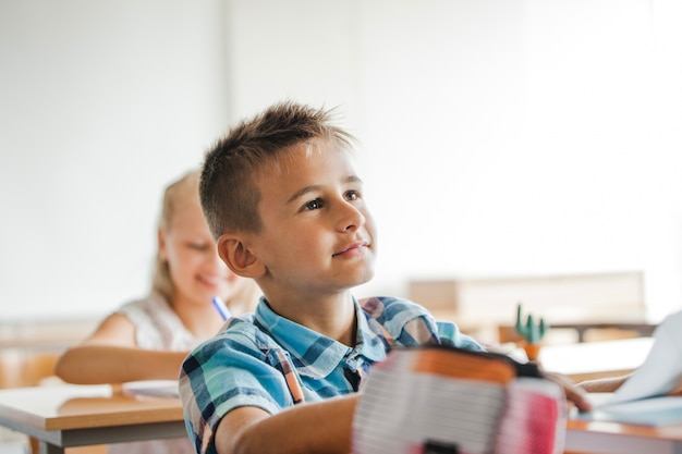 学校の机に座っている若い男の子