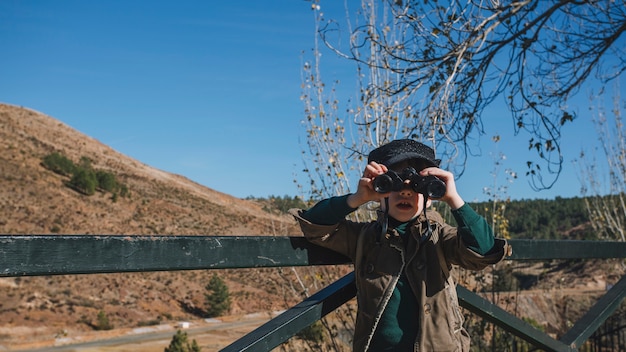 Free photo young boy standing with binoculars