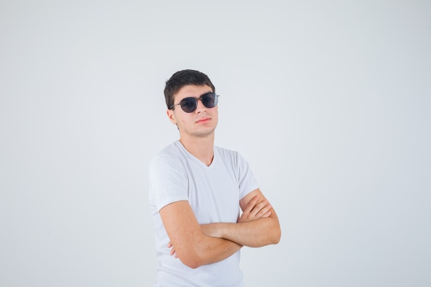 Young boy standing with crossed arms in t-shirt and looking confident. front view.