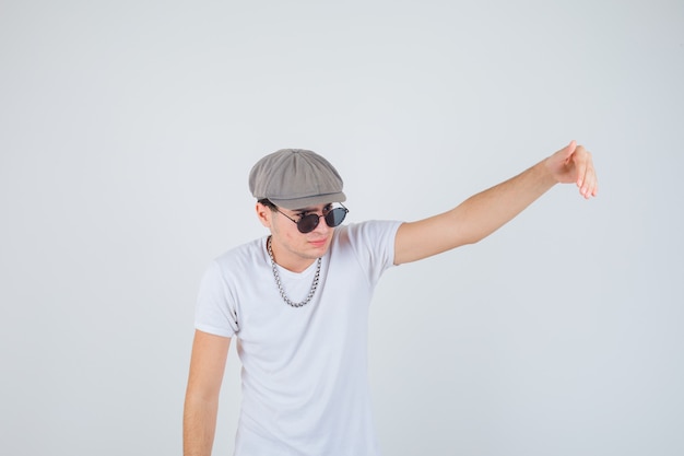 Young boy in t-shirt, hat inviting to come and looking confident , front view.