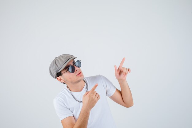 Young boy in t-shirt, hat pointing away and looking focused , front view.