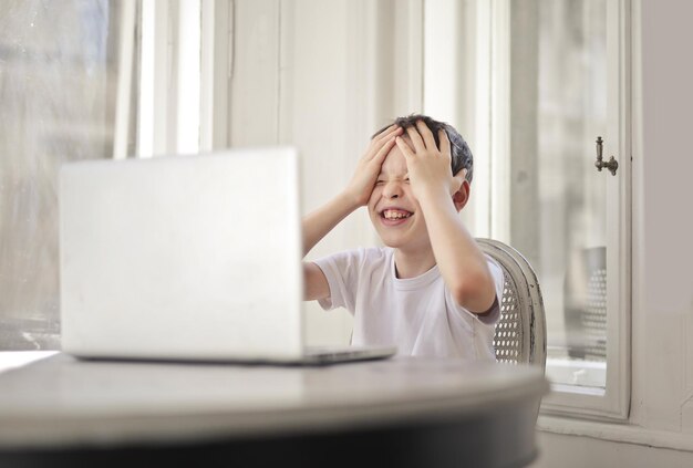 不幸な少年はコンピューターの前で喜ぶ