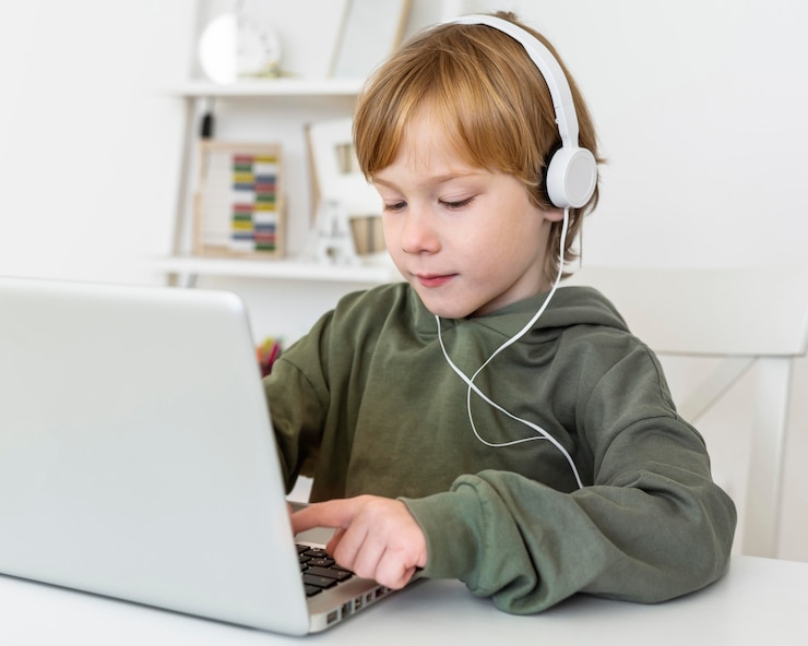Free Photo young boy using laptop with headphones