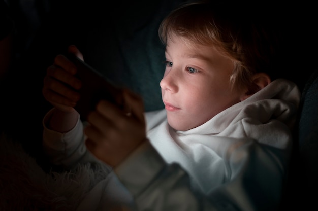Young boy using smartphone in bed at night