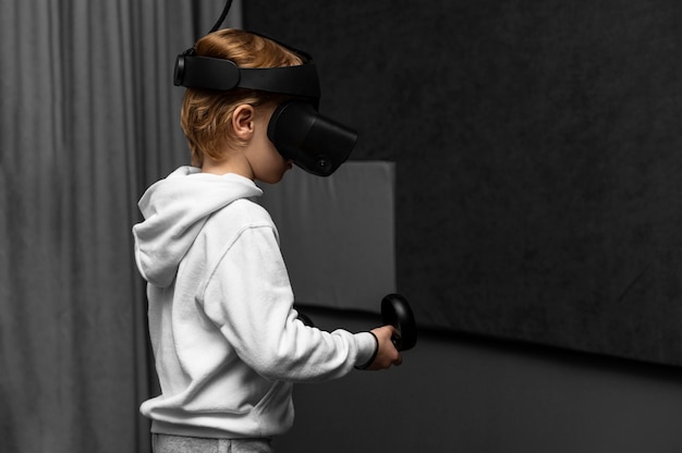 Foto gratuita ragazzo che utilizza le cuffie da realtà virtuale con lo spazio della copia
