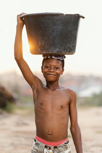 Free photo young boy with basin on head