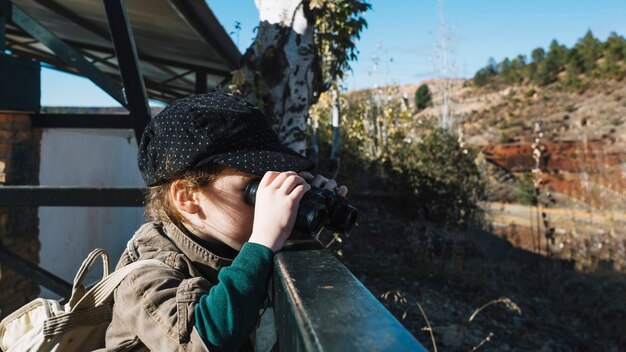 Young boy with binoculars at handrail