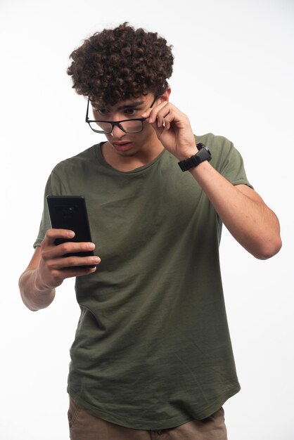 Young boy with curly hairs checking messages and gets surprized. 