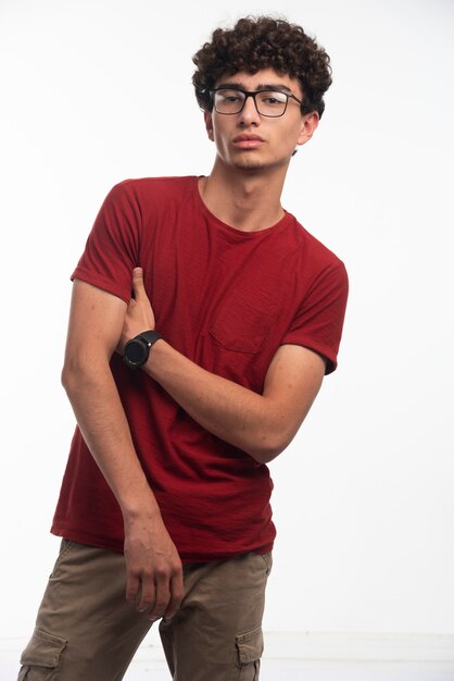 Young boy with curly hairs holding arms under shoulders. 