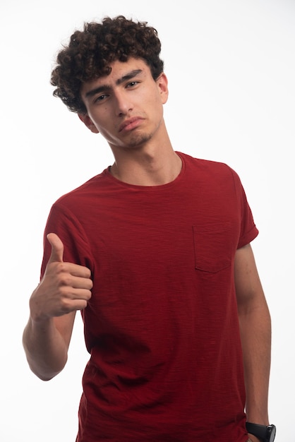 Free photo young boy with curly hairs makes thumb up.